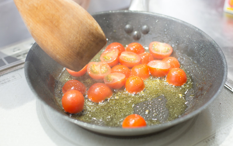 写真：フライパンでプチトマトをオリーブオイルで炒めている様子