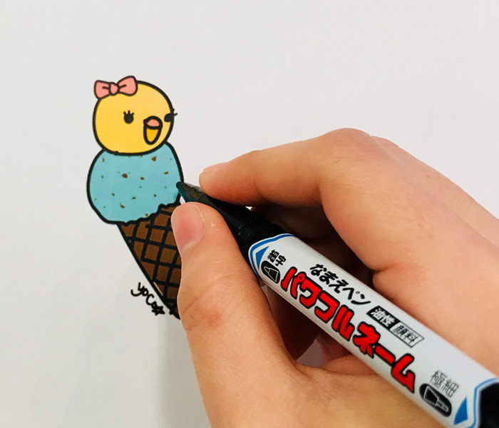 写真：マジックでヒヨコを模したアイスクリームのイラストを描いている様子。