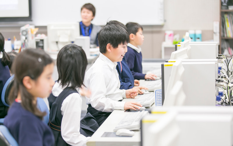 写真：笑顔でパソコンを操作する生徒