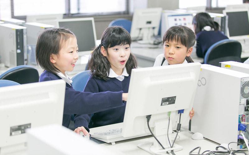 写真：パソコンを操作している生徒が驚いた様子の表情をしている。その横には笑顔の生徒。