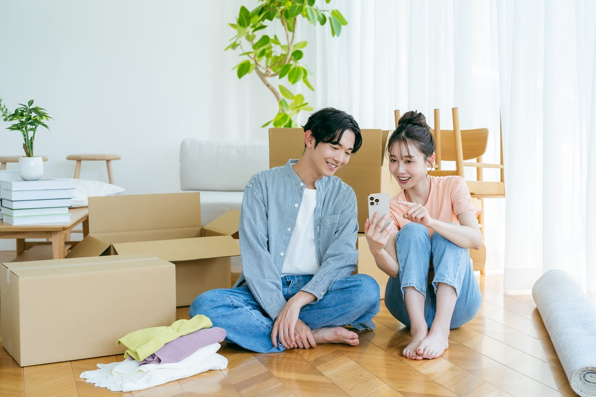 引越し作業中にスマートフォンを操作する男女のイメージ
