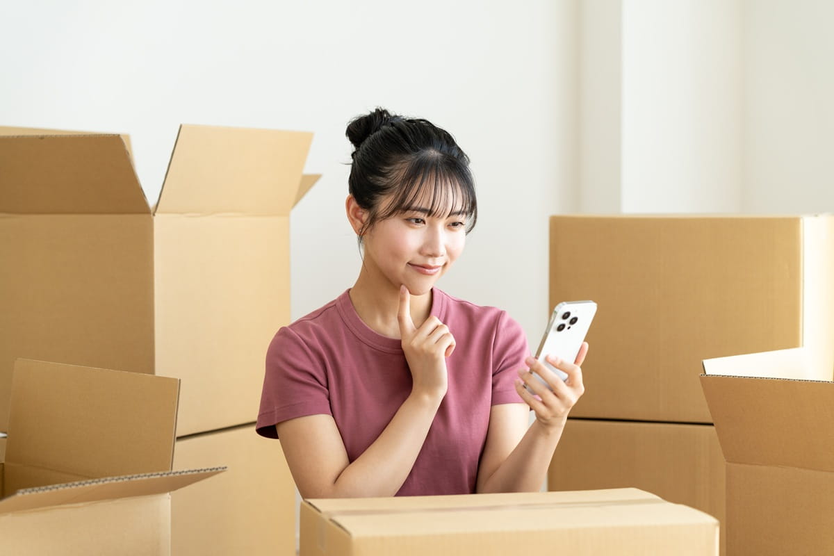 引越し作業中にスマートフォンを操作する女性のイメージ