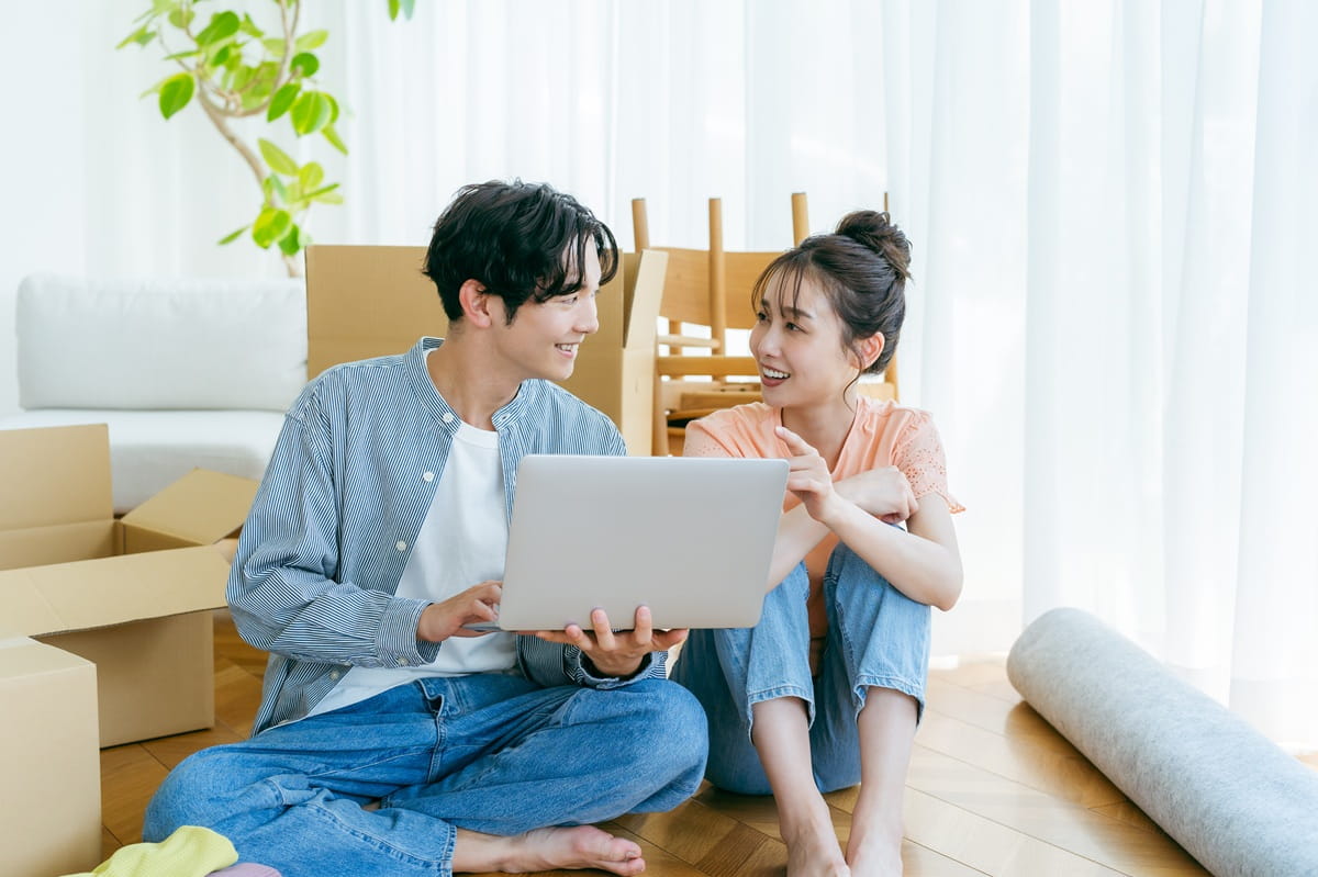 引越し作業中にスマートフォンを操作する男女のイメージ