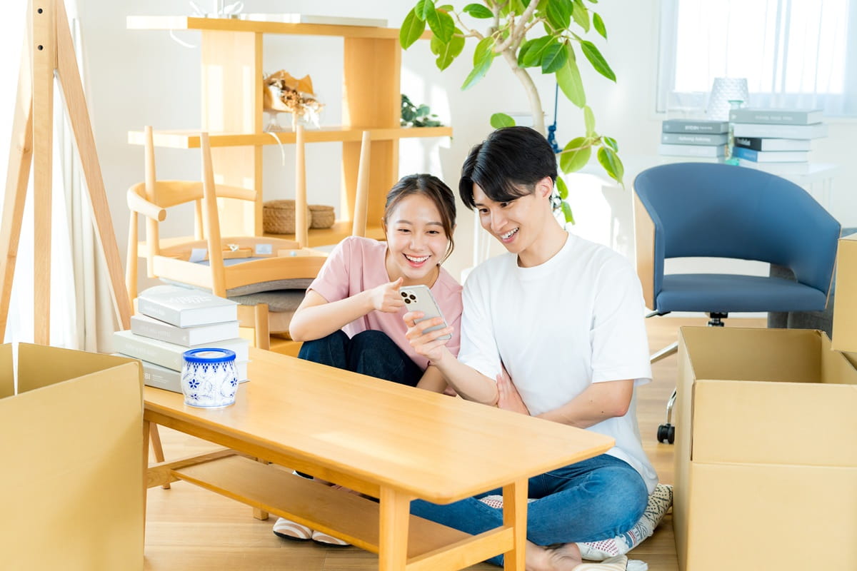 引越し作業中にスマートフォンを操作する男女のイメージ